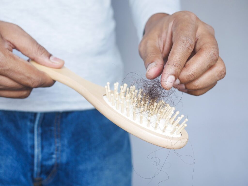Hombre quitando pelo caído de un cepillo de madera